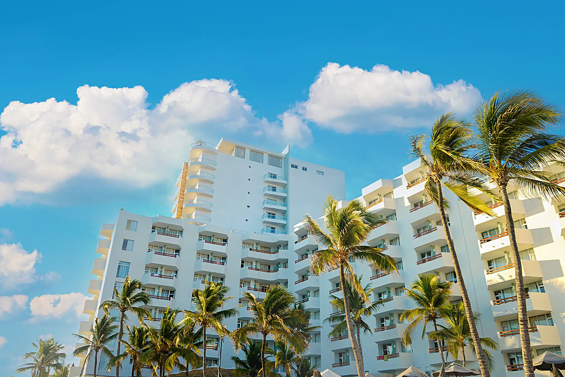 Facade of Oceano Palace hotel with rooms overlooking the sea and palm trees in Mazatlán